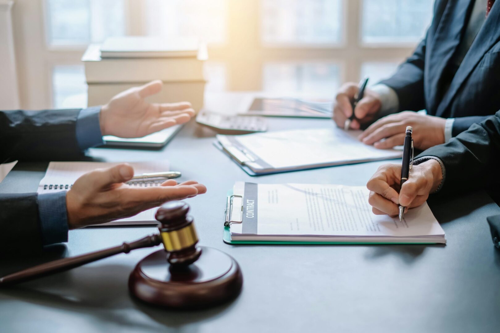 Legal professionals discussing documents with a judge's gavel on the table.