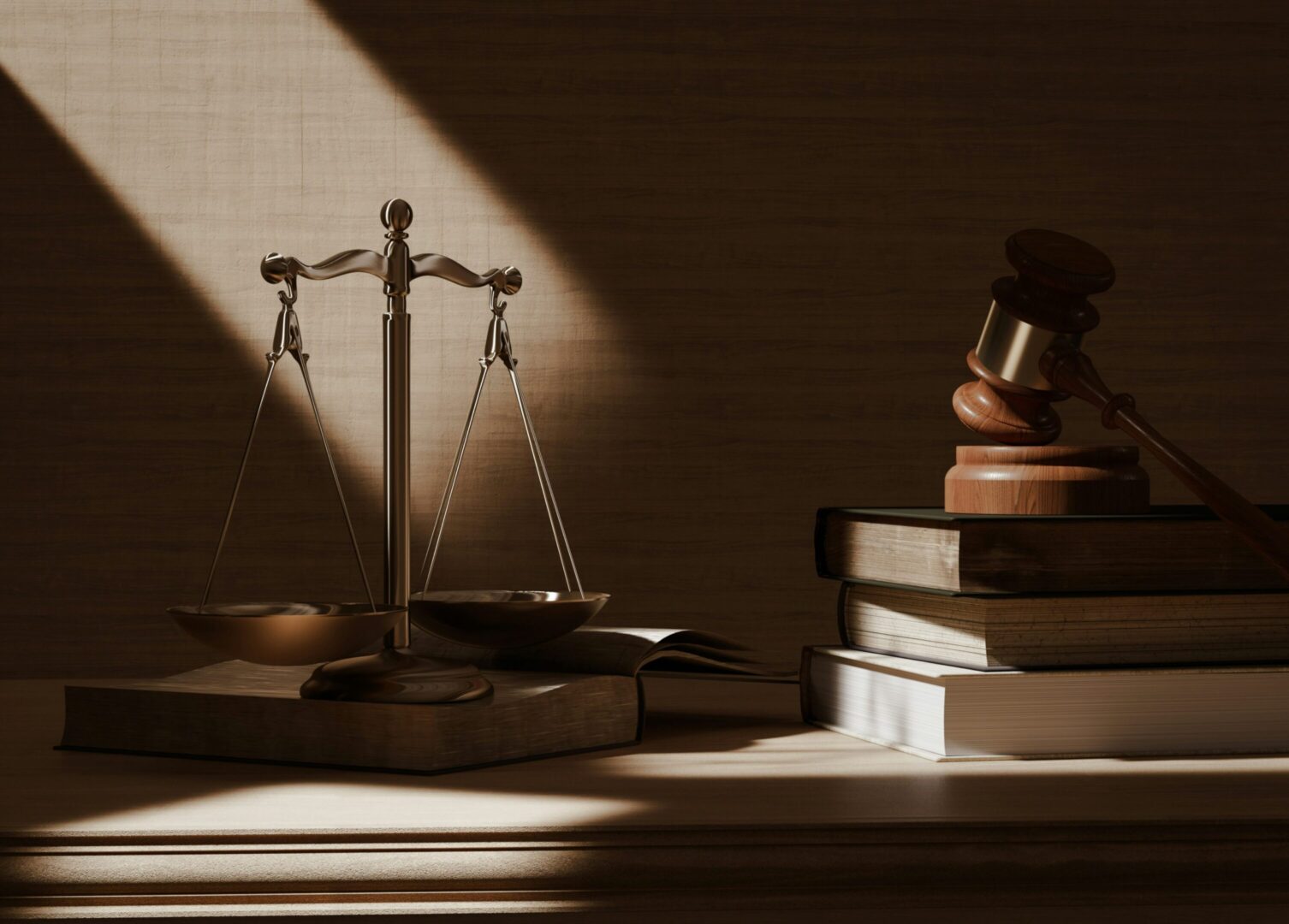 Justice scales and gavel on books in a dimly lit room.