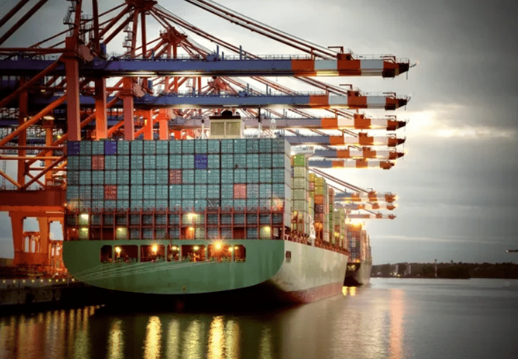Container ship docked at a busy port with cranes unloading cargo.