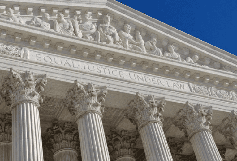 Close-up of Supreme Court building facade with pillars and inscription.
