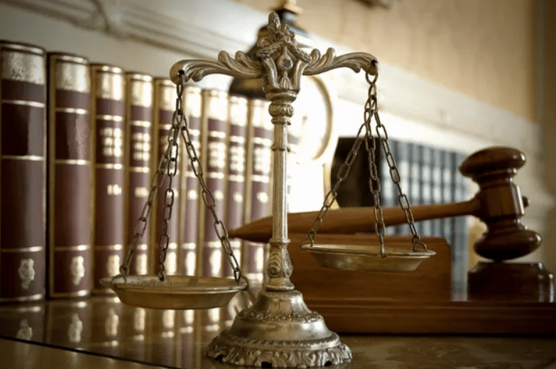 Antique brass scales of justice with law books in the background.