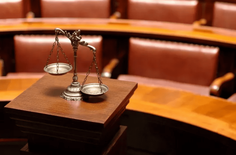 Scales of justice on a wooden desk in a courtroom.